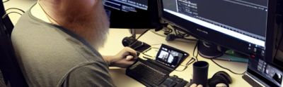 Man sitting at a desk coding a website with multiple screens.