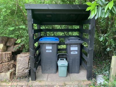 Bin store painted black with the bins inside.