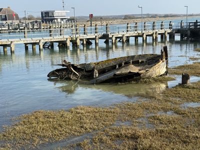 A half sunken hulk of an old wooden fishing trawler at Rye harbour.