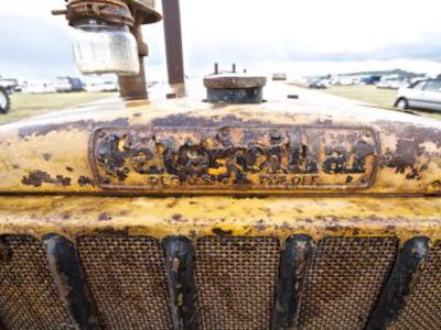 Front of bonnet of a rusty yellow catapillar tractor.